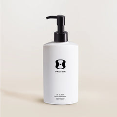 White bottle with black pump and 'One Skin' logo on a beige background